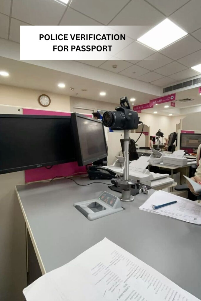 Passport office counter showing biometric camera, computer systems, and documents during the police verification process for passport application in India.